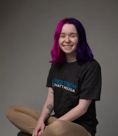 Shelby, sitting cross-legged in a Pest Tech T-shirt