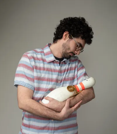 Andrew, cradling a bowling pin like a baby